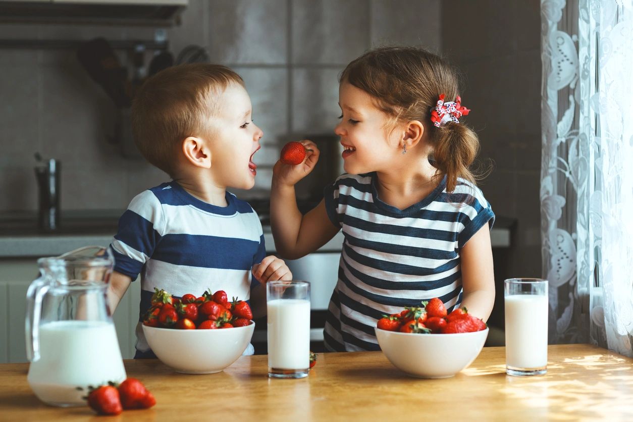 two kids with strawberries in bowl